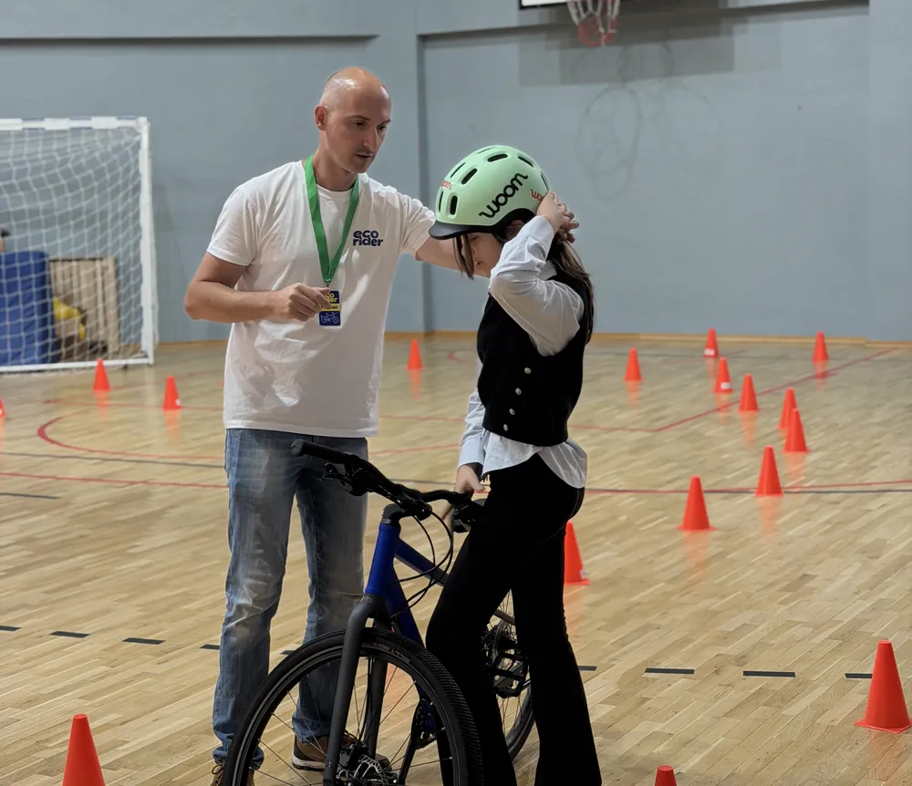 Trainer EcoRider care îi potrivește casca unei fetițe înainte de traseu